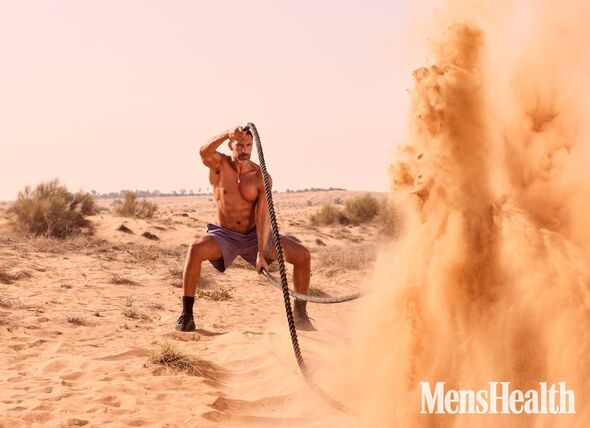 An individual is engaged in a physically demanding activity in an arid desert environment, wielding a long pole while navigating