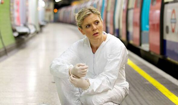 An individual in a white protective suit kneels on the edge of a subway platform, with a train visible in the background. The se
