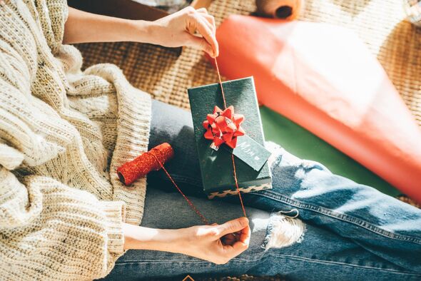 Woman wrapping Christmas gifts at home. Packing the Christmas presents.