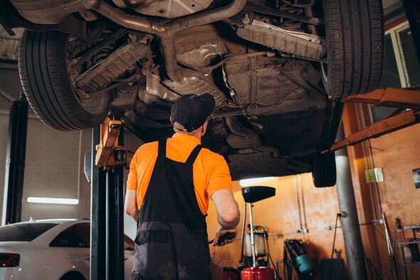 Mechanic examining under the car at the repair garage. Low angle view. High quality photo