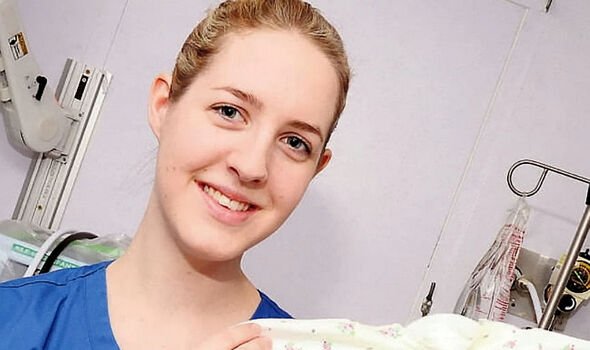 A nurse smiles as she holds a babygrow