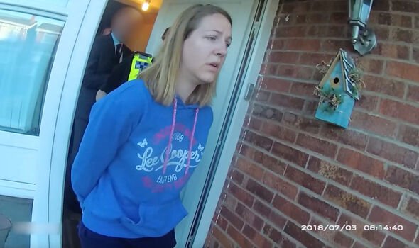 A woman leaves a house in handcuffs