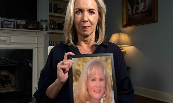 A woman holds a photo of another woman smiling