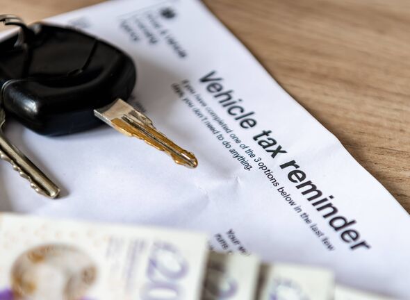 A vehicle tax reminder document of a desk with car keys and money.