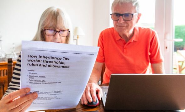 A senior married couple in their 70s study inheritance tax documents sitting down in their living room at home
