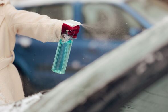 Hand of a Driver Using De-icer Spray for Windshield