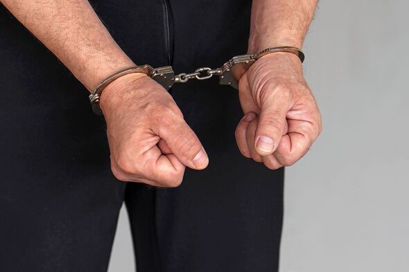 Criminal hands locked in handcuffs. Close-up view