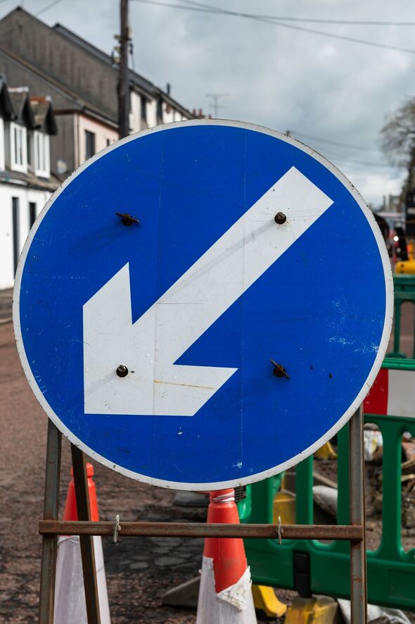 Blue traffic direction sign besides roadworks