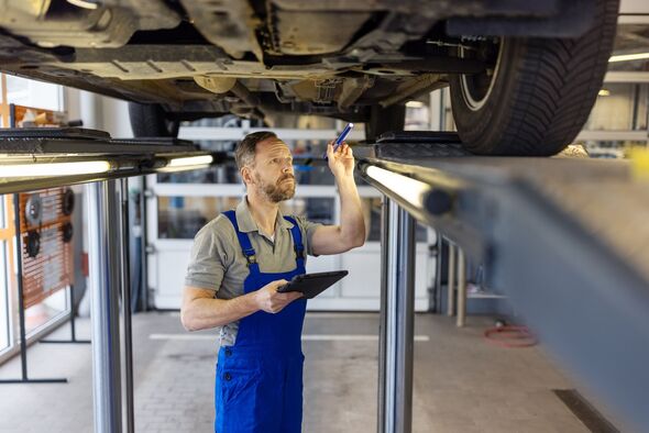 Repair man inspecting the vehicle before maintenance at service station