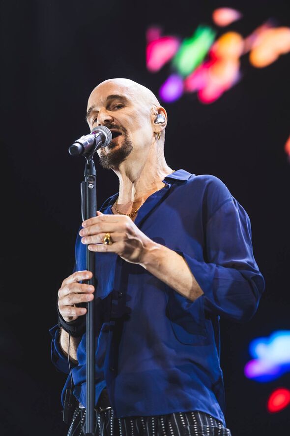 An individual in a blue long-sleeve shirt passionately singing into a microphone on a stage.