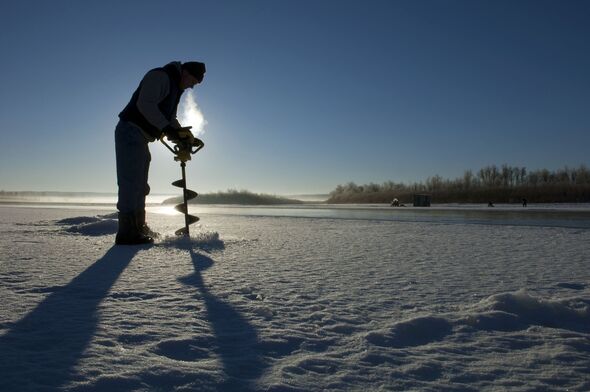Ice fisherman drilling hole in ice on the Missouri River, North Dakota