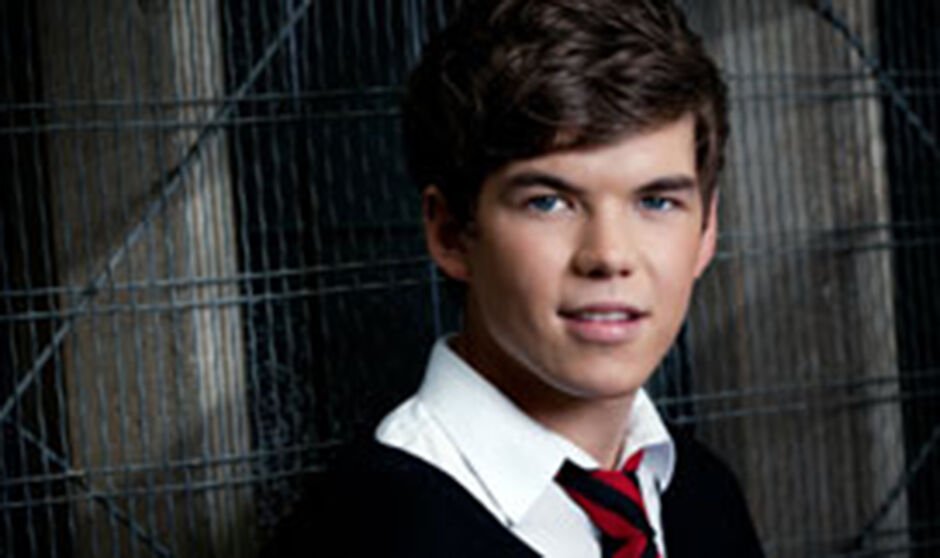 A boy in a school uniform smiles