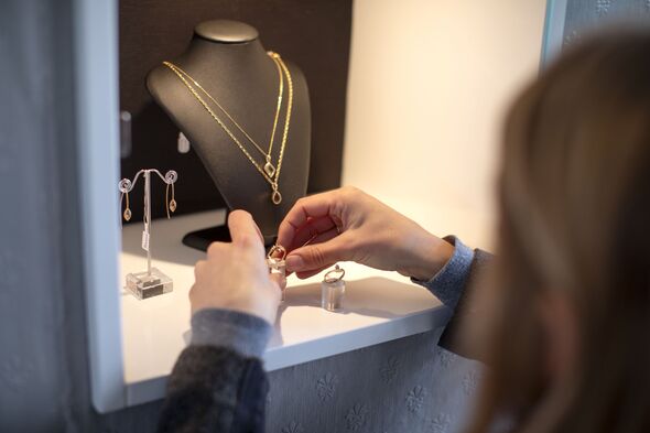 A jewellery store owner arranging her display case.