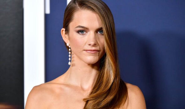A woman with long hair smiles in a promotional setting