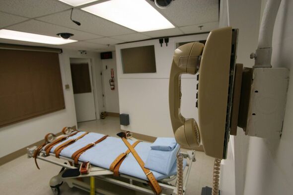 An image depicts an empty execution chamber within a correctional facility. The room features a stark, clinical setting with whi