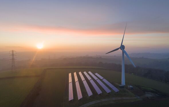 Aerial view of wind turbine and solar panels at sunset