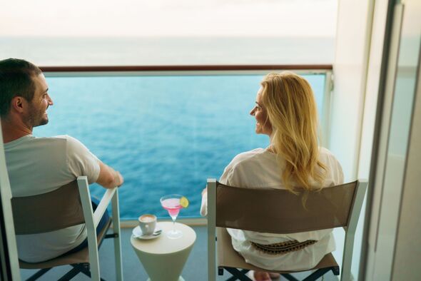 A couple is sitting on a deckchair on the balcony of the cruise ship and enjoying their drinks