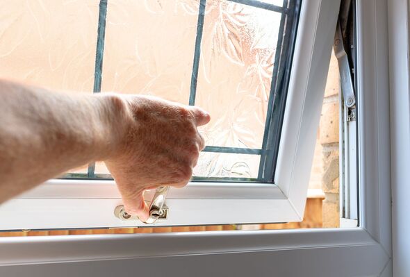 Home owner seen opening a newly fitted PVC double glazed window in a bathroom.