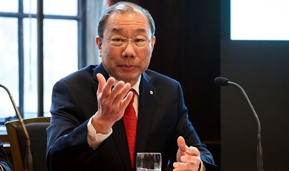 A man speaks into a microphone whilst sitting at a table