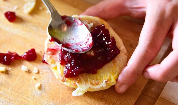 Picture of someone adding strawberry compote to a scone