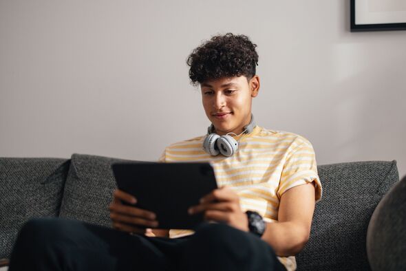 Young Teen Boy with Headphones Enjoying Tablet Time at Home