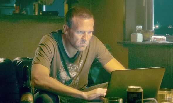 A man sits and looks at a laptop