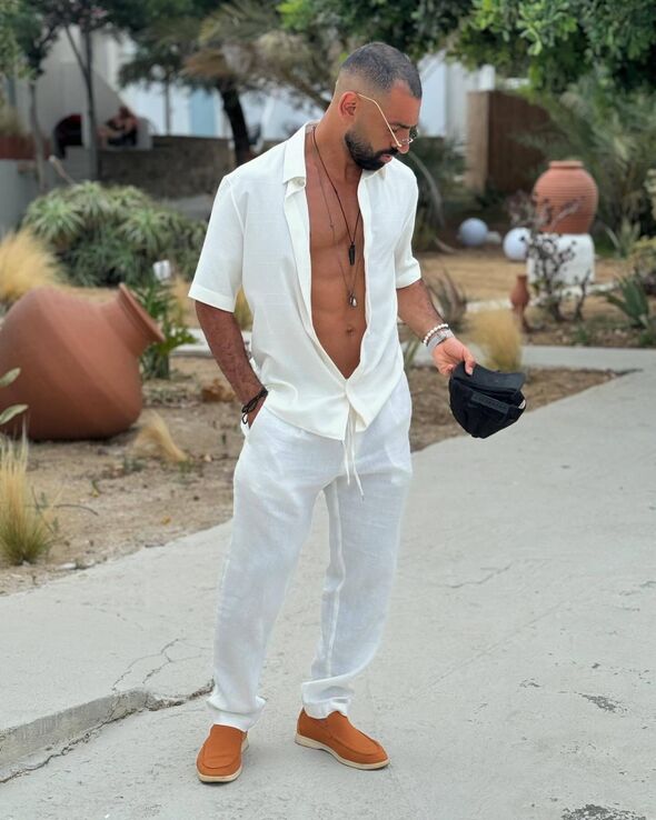 Mohamed Salah posing for a photo with an open shirt and white trousers