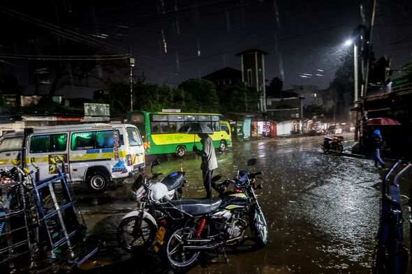 Pedestrians walk through the rain in the Kibera Slums