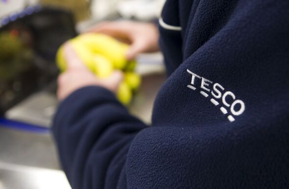 Employee scanning bananas at the checkout of a Tesco supermarket