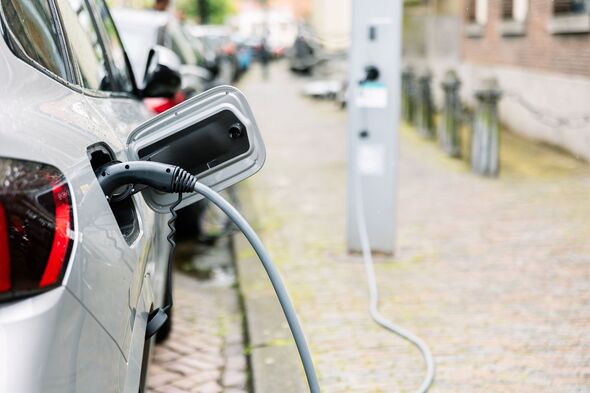 Electric car charging through plug on street.