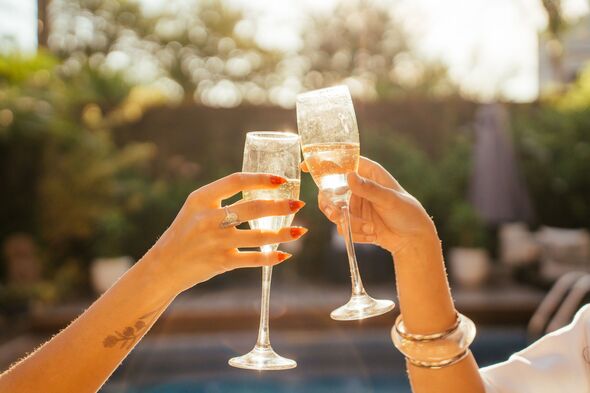 Hands holding a champagne glass and toasting.