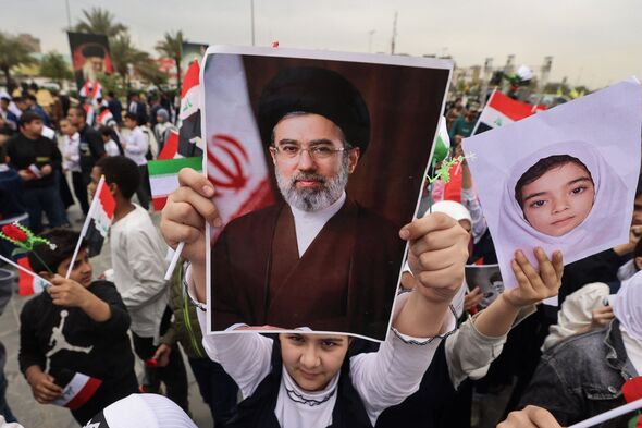 Schoolgirl holds up a poster of Mojtaba Khamenei