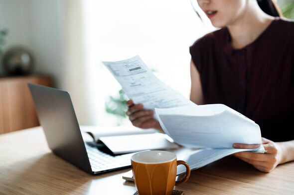 Cropped shot of Asian woman sitting at dining table, handling personal finance with laptop. She is making financial plan and pla