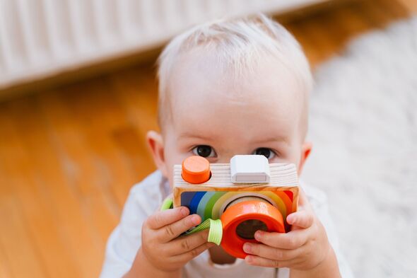 Toddler holding toy camera in hands. Baby pretending to take photos during playtime. Creative indoor play. Montessori education. Happy childhood. Chil