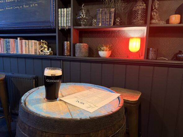 A pint of Guinness on a barrel table inside The Grapes pub in London