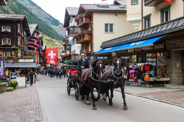 Traditional retro horse-drawn carriages carrying tourists in Zermatt, Switzerland