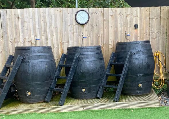 A view of three cold water barrelts in front of a fence at the sauna