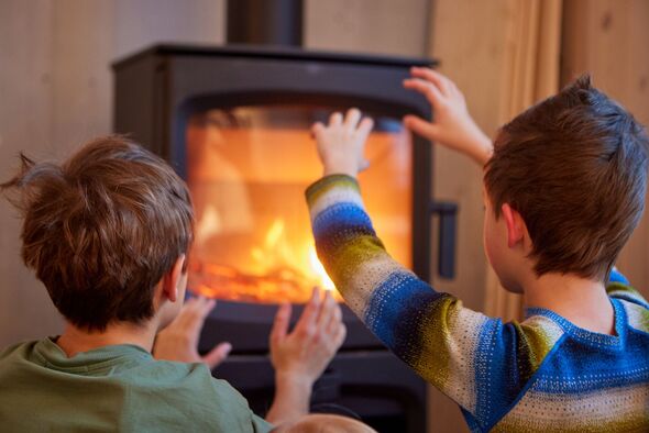 Children warming hands by cozy wood burning stove