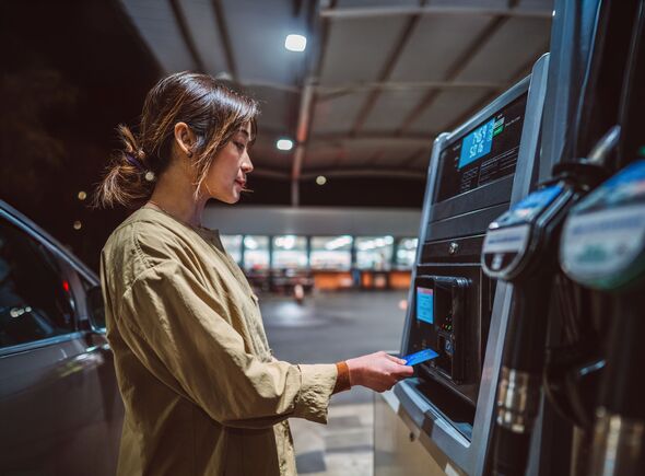 Convenience on the Go: Young Asian woman doing payment through credit card after refuelling her car at gas station