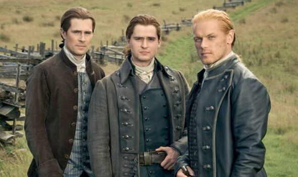 Three men stand together in a field