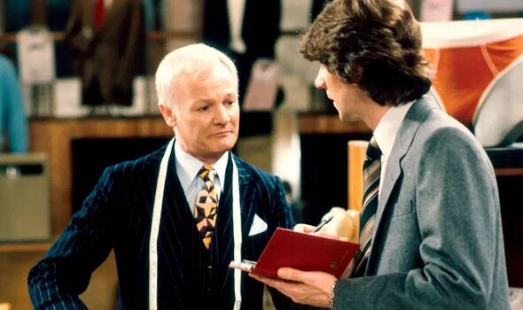 Two individuals dressed in formal attire, likely in a professional setting, are engaged in a conversation while one of them hold