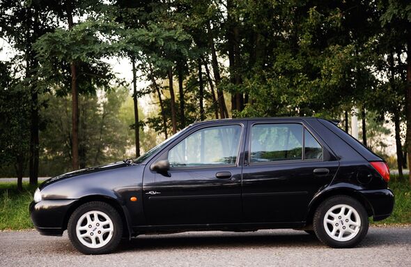 Ford Fiesta black 2000 year, parked in a parking lot in the forest, side view. stock photo