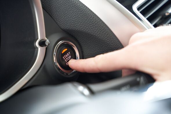 Driver pressing car engine start button in a modern car.