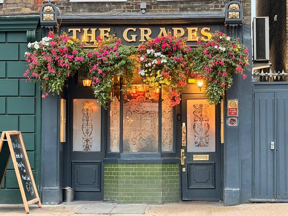 The exterior of Sir Ian McKellen's pub, The Grapes, with colourful hanging baskets and frosted glass windows