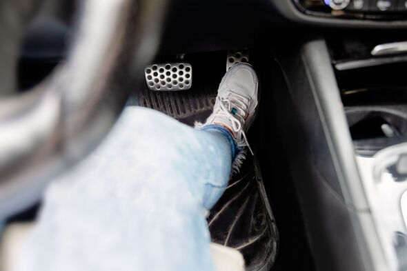 Feet in white sneakerson on car gas pedal close-up