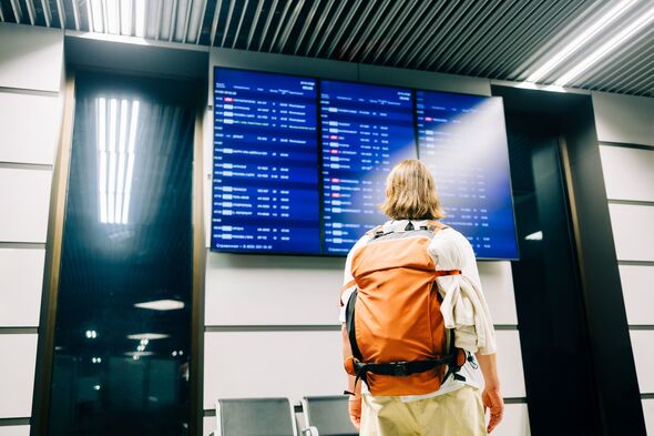 Traveler checking flight departure schedule at airport terminal