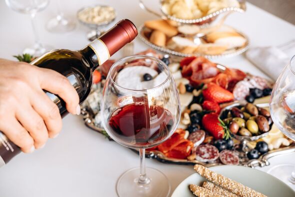 Pouring Red Wine Into Glass On Dining Table