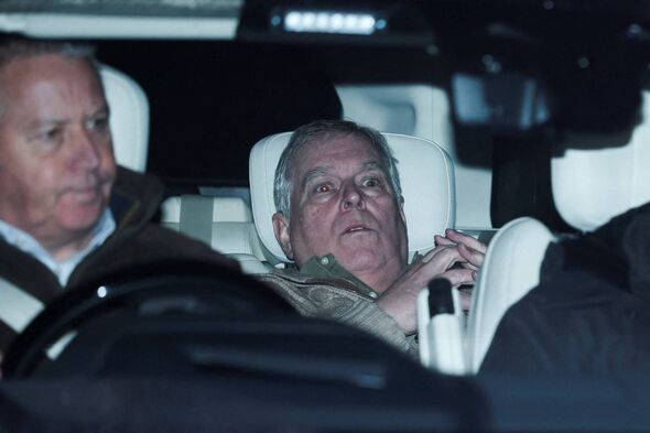 An individual wearing glasses is seated in the front passenger seat of a vehicle, accompanied by another individual who appears