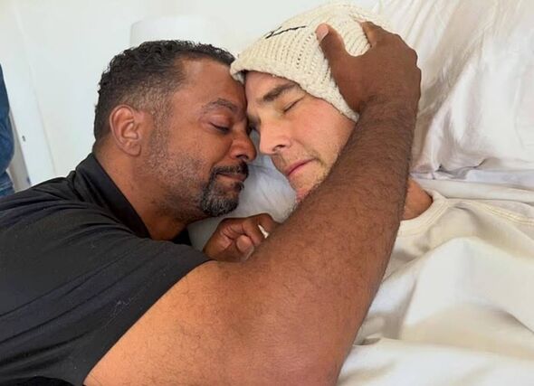 An individual offering comfort and support to another person lying in bed, demonstrating a profound emotional connection and car