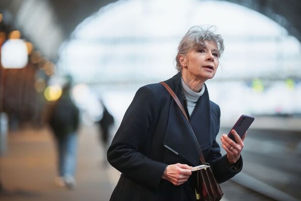 Elegant Senior Woman Using Smartphone at Train Station Platform